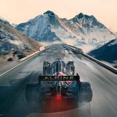 a red and white race car driving down a road with mountains in the back ground