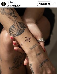 two women with tattoos on their arms holding each other's hands and one has a tattoo on her arm