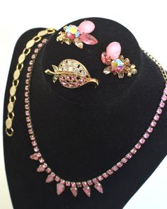 Vintage pink set w Sara Cov bracelet Set includes a necklace, earrings, bracelet, and brooch. The necklace is made up of individual pink stones with the center having teardrop milky pink stones in a silver tone metal, measuring 16 inches in length from end to end. The clip back earrings are beautifully designed in a gold tone metal with a clear pink stone, milky pink stone, and an iridescent pink stone, measuring 1 ⅛ inches in length. The brooch is a leaf shape with pink and clear rhinestones in Pink Jeweled Jewelry For Formal Occasions, Formal Pink Jeweled Jewelry, Pink Teardrop Jewelry For Formal Occasions, Formal Pink Teardrop Jewelry, Pink Teardrop Jewelry For Jewelry Making, Vintage Pink Formal Jewelry, Pink Costume Jewelry For Party, Pink Formal Costume Jewelry, Pink Costume Jewelry For Formal Occasions