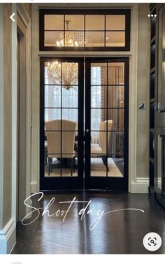 an entry way with glass doors and chandelier above the door that leads to a formal dining room