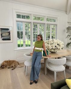 a woman sitting at a table with her dog in front of the dining room window