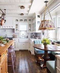 a large kitchen with wooden floors and white walls, along with lots of counter space