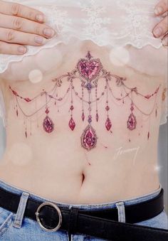 a woman's stomach with pink jewels and chains on her back, in front of white lace