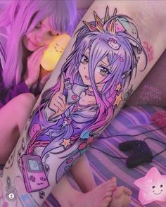 a woman with tattoos on her leg laying down next to a pink cat and purple hair