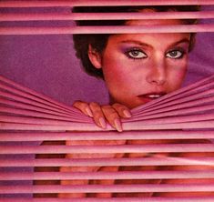 a woman peeking out from behind pink blinds