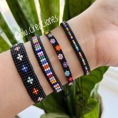 three bracelets with beads are on the arm next to a potted green plant