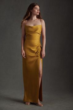 a woman in a long yellow dress posing for the camera