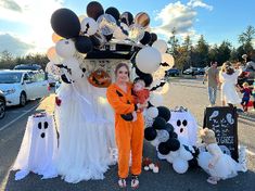 a woman in an orange jumpsuit standing next to a car decorated with halloween decorations