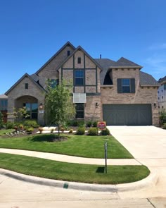 a large house that is in the middle of a yard with grass and bushes around it