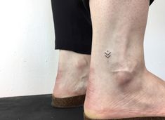 a woman's foot with a small tattoo on her left ankle and an arrow in the middle