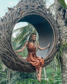 a woman sitting in a bird nest on top of a palm tree with her legs spread out