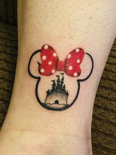 a minnie mouse tattoo on the ankle with a castle in it's centerpiece