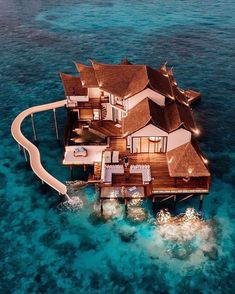 an aerial view of a house in the ocean with lights on it's roof