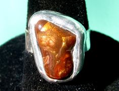 This lovely handmade ring features a natural Fire Agate stone, from the Deer Creek Mine in Arizona. The Fire Agate cabochon looks brown in the shade, but in the sun it displays rainbow iridescence and reveals an botryoidal (bubbly) interior structure. The band of the ring is recycled Sterling Silver, and the stone is bezel set with lead free silver bearing soft solder. Designed and handmade by Clare Thanhauser, one of a kind. 100% natural untreated Fire Agate size 5 1/4 ring 15x9mm Fire Agate 5m Unique Brown Rings For Gift, Brown Oval Agate Rings, Oval Brown Agate Rings, Unique Brown Oval Rings, Brown Natural Stone Rings, Artisan Brown Jewelry With Natural Inclusions, Brown Natural Stone Ring, Artisan Brown Gemstone Rings, Brown Large Stone Ring