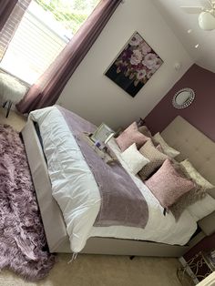 a bedroom with purple and white bedding, pink rugs and pictures on the wall