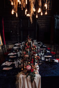 a long table is set with candles, flowers and wine glasses for an elegant dinner