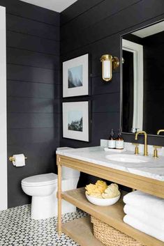 a white toilet sitting next to a sink in a bathroom under a large mirror and gold faucet