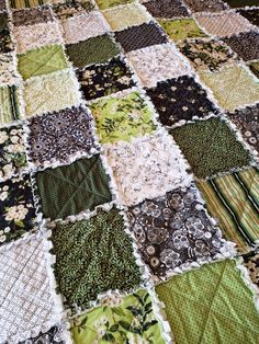 a green and black patchwork quilt on top of a bed