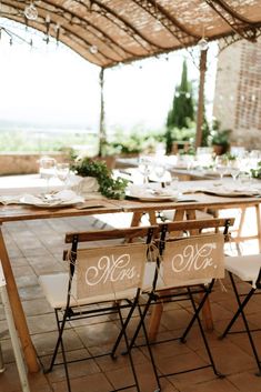 an outdoor dining area with tables and chairs set up for a wedding reception under a pergolated roof