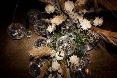 a table topped with disco ball vases filled with white flowers and pamodia