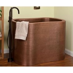 a large copper bath tub in the corner of a room with wood floors and pictures on the wall