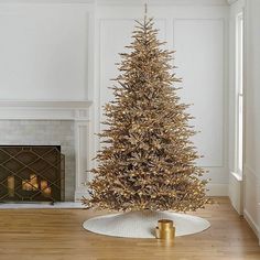 a christmas tree in a living room next to a fire place with a candle on the floor