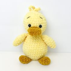 a crocheted yellow duck sitting on top of a white table next to a wall