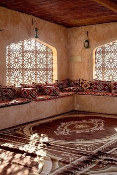 the sun shines through two large windows in an ornately decorated room with decorative rugs