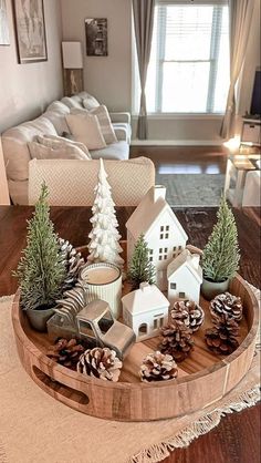 a wooden tray with pine cones and small houses on it