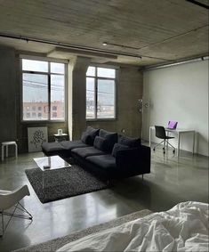 a living room filled with furniture next to two large windows on the side of a building