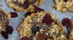 cookies with chocolate and cranberries are on a baking sheet, ready to be eaten