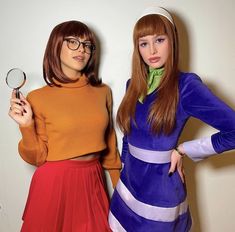 two young women dressed in costumes holding magnifying glasses and standing next to each other