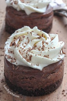 two chocolate cakes with white frosting and sprinkles on a wooden table