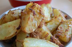 cooked potatoes in a white bowl on a table next to a red and white cup