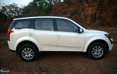 a white suv parked in front of a rocky cliff