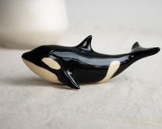 a black and white orca whale figurine sitting on a table next to a cup