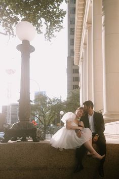 a bride and groom sitting on steps in front of a lamp post at the end of their wedding day