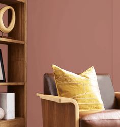 a brown leather chair sitting in front of a book shelf filled with books and pillows