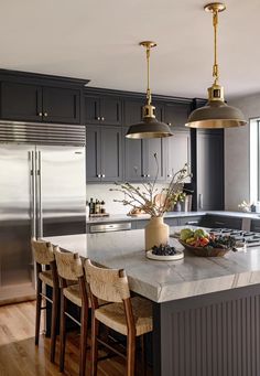 a large kitchen with an island and two pendant lights over it's stove top