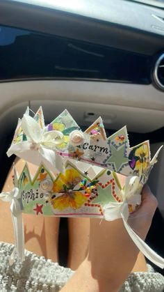 a person wearing a paper crown sitting in the back seat of a car with her hand on the steering wheel