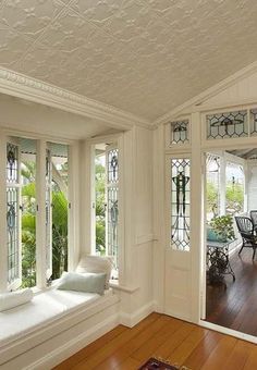 a living room filled with lots of windows next to a table and chairs on top of a hard wood floor