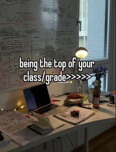 a laptop computer sitting on top of a desk next to a window with writing on it