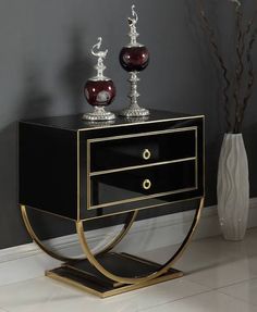 a black and gold side table with two vases on top