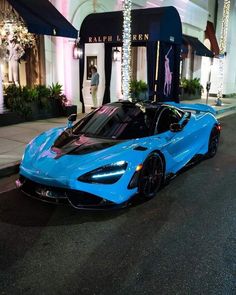 a blue sports car parked in front of a building with lights on it's windows