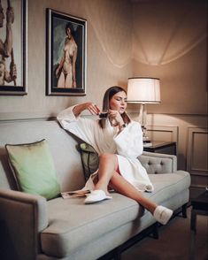 a woman sitting on top of a couch next to a lamp