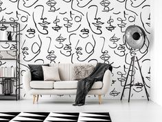 a white couch sitting in front of a wall with black and white designs on it