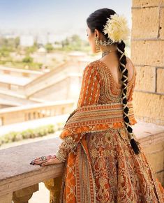 a woman in an orange and gold dress looks out over the city from her balcony