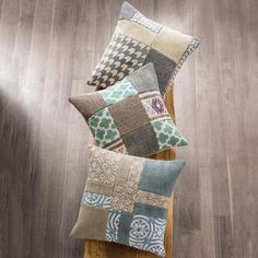 four pillows are stacked on top of a wooden bench in front of a wood floor