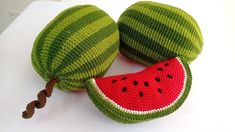 two knitted watermelon cushions sitting on top of a white cloth covered table