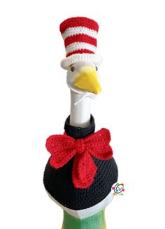 a stuffed bird wearing a knitted hat and sweater on top of a wine bottle